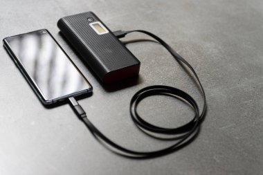 Cep telefonu masanın üzerinde yükleniyor. Ekstra pil kavramı.