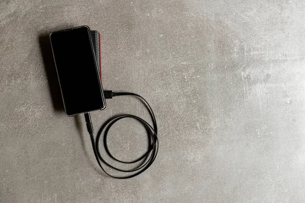 Çalışma masasında harici bataryası olan bir cep telefonu. Teknik Aygıt Paylaşımı.