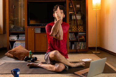 Kompleks yoga yapan adam online talimatlarla poz veriyor. Ev yoga konsepti.