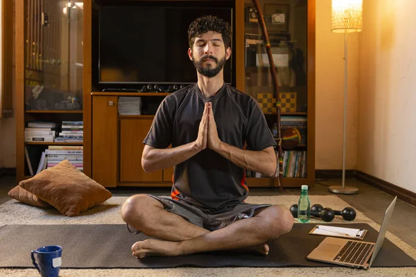 Young Hispanic man doing meditation at his home. Home yoga concept.