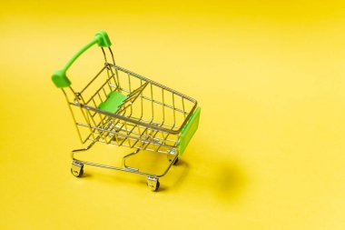 Sarı arka planda alışveriş arabası. Çevrimiçi ticaret kavramı.