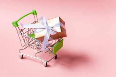 Pembe arka planda hediye arabası. Çevrimiçi ticaret kavramı.