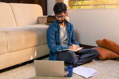 Evinde çalışırken not alan bir adam. Ev kavramından çalışmak.