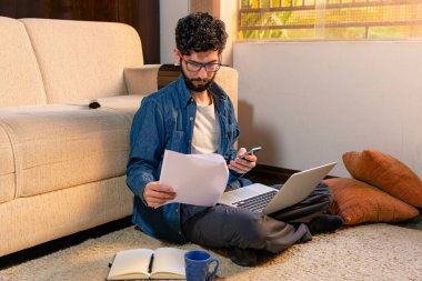 İspanyol adam evrakları kontrol ediyor ve cep telefonunu ofisinde yerde tutuyor..