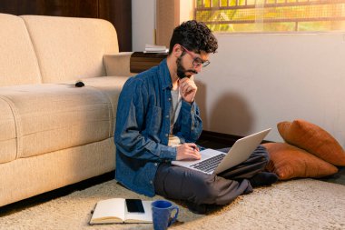 Ofisinde yerde oturan bir işçi. Ev ödevi konsepti.