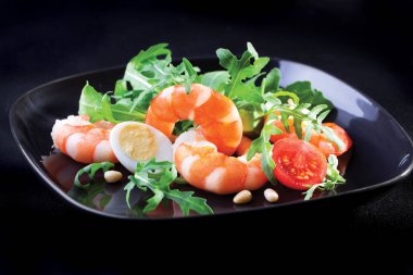 Kral'ın salata karides ve rukola siyah bir tabak içinde