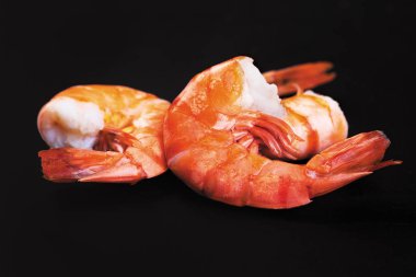 Siyah bir zemin üzerine üç haşlanmış karides