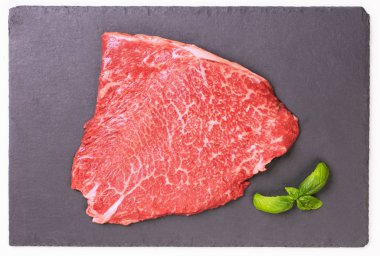 Fresh marbled beef steak on a black slate board
