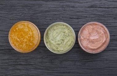 Siyah ahşap zemin üzerinde çeşitli renkte krema kutuları, üst görünüm