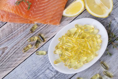 Bir avuç dolusu omega 3 somon fileto ve somon somonu ahşap bir masada.