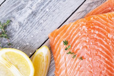 Tahta zemin üzerinde kekik ve limon filizi olan taze somon filetosu.