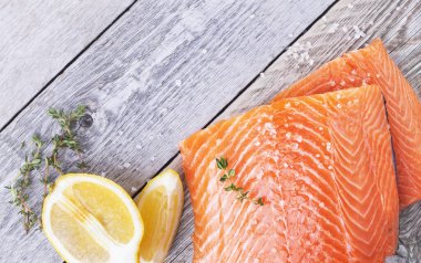 Tahta zemin üzerinde kekik ve limon filizi olan taze somon filetosu.