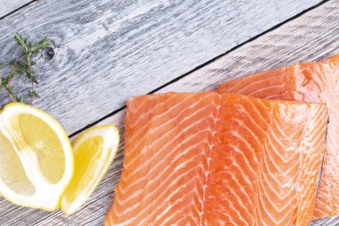 Tahta zemin üzerinde kekik ve limon filizi olan taze somon filetosu.