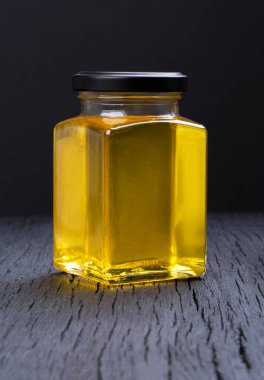 Siyah arka planda şeffaf bir kavanozda bal