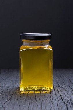 Siyah arka planda şeffaf bir kavanozda bal