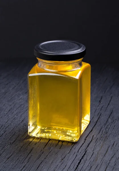 Siyah arka planda şeffaf bir kavanozda bal