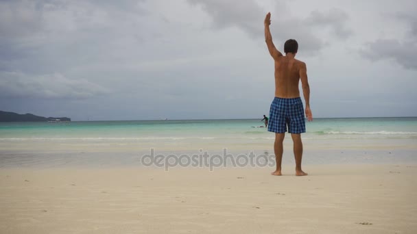 Man gör morgonövningar på stranden. — Stockvideo