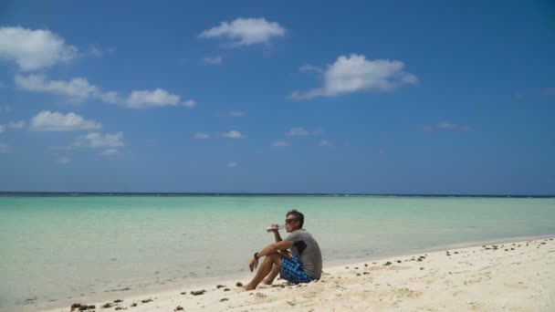 Man die bier drinkt op het strand. — Stockvideo