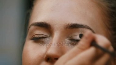 Makyöz, genç bir kadının profesyonel makyajını yapıyor.