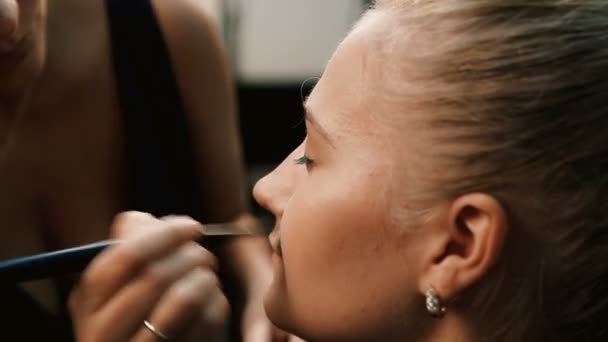 Maquillar artista haciendo profesional maquillaje de mujer joven — Vídeos de Stock