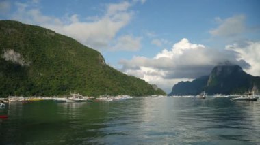 Adalı deniz manzaralı, dağlı, denizde kayıklı.