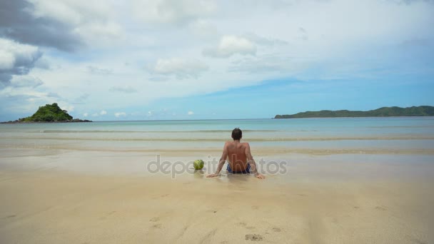 Человек, сидящий на пляже. — стоковое видео