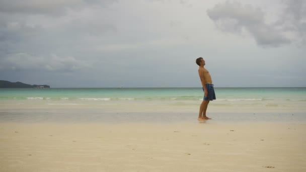 Человек делает утренние упражнения на пляже. — стоковое видео