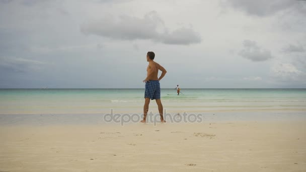 Hombre haciendo ejercicios matutinos en la playa. — Vídeo de stock