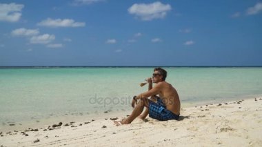 Kumsalda bira içen adam.