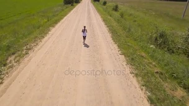 Menina corre na estrada em um campo.Vista aérea . — Vídeo de Stock