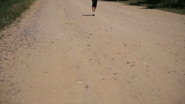 Chica corre en la carretera en un campo . — Vídeo de stock