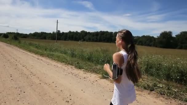 Girl runs on the road in a field. — Stock Video