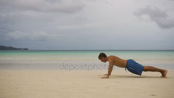 Man doing push-ups on the beach — Stock Video