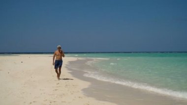 Adam sahilde bir cep telefonu ile.