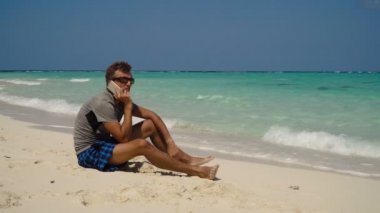 Adam sahilde bir cep telefonu ile.