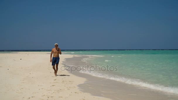 Un uomo con un cellulare sulla spiaggia . — Video Stock