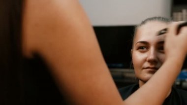 Makyöz, genç bir kadının profesyonel makyajını yapıyor.