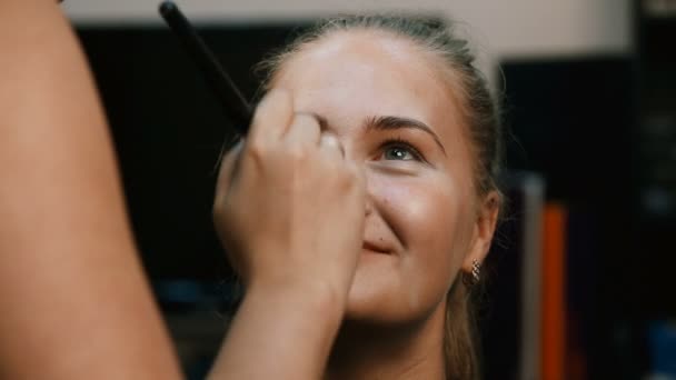 Maquillar artista haciendo profesional maquillaje de mujer joven. — Vídeos de Stock