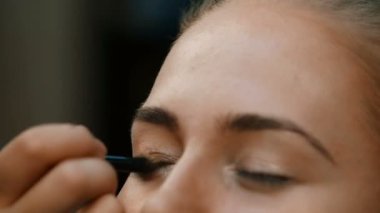 Makyöz, genç bir kadının profesyonel makyajını yapıyor.