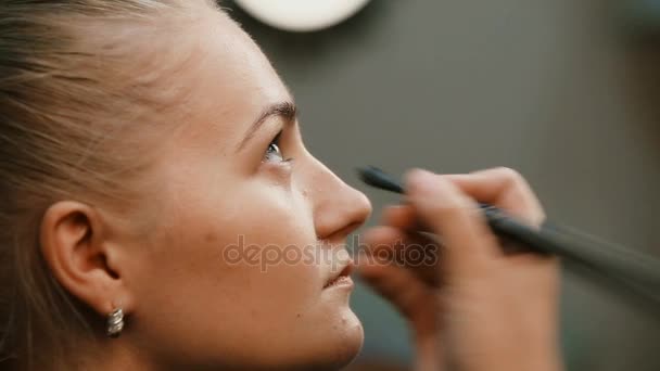 Maquillar artista haciendo profesional maquillaje de mujer joven — Vídeos de Stock