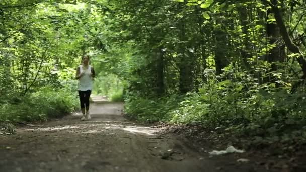 Menina corre na estrada em um campo . — Vídeo de Stock