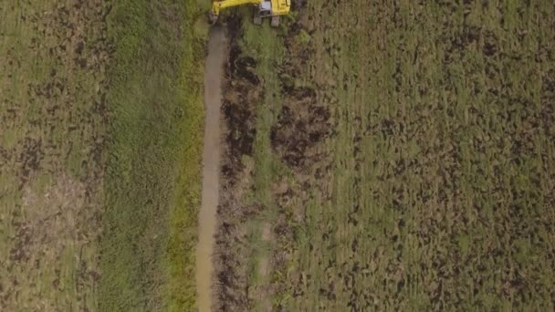 Graafmachine graven van een loopgraaf in het veld. Luchtfoto video. — Stockvideo