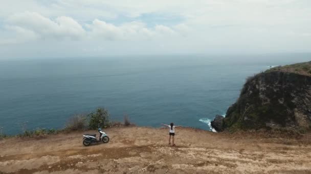 Meisje dat op een klif staat en naar de zee kijkt. Bali, Indonesië — Stockvideo