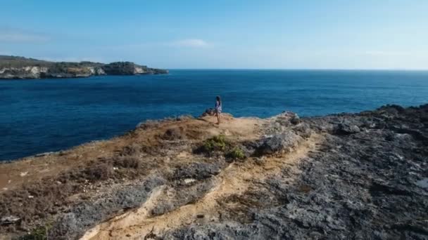 Uçurumun kenarında duran ve denize bakan bir kız. Bali, Endonezya — Stok video