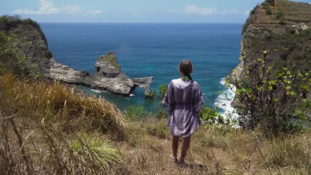 Девушка, стоящая на скале и смотрящая на море. Бали, Индонезия — стоковое видео
