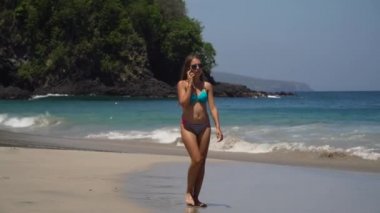 Sahilde yürüyüş cep telefonu olan kız. Bali, Endonezya.