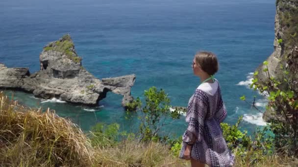 Menina de pé em um penhasco e olhando para o mar. Bali, Indonésia — Vídeo de Stock