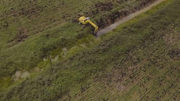 Graafmachine graven van een loopgraaf in het veld. Luchtfoto video. — Stockvideo