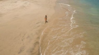 Kumsalda yürüyen bir kız. Bali, Endonezya.