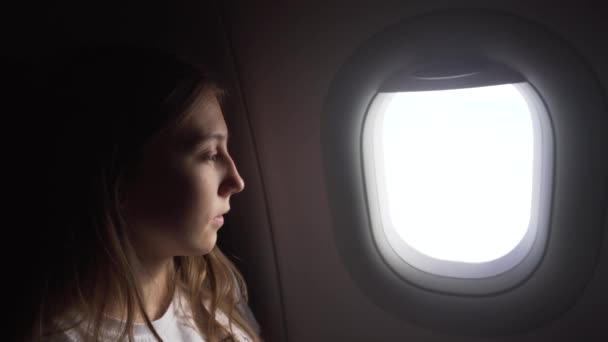 Mädchen sitzt am Flugzeugfenster und schaut nach draußen. — Stockvideo